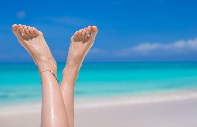 Close up of female feet on white sand beach