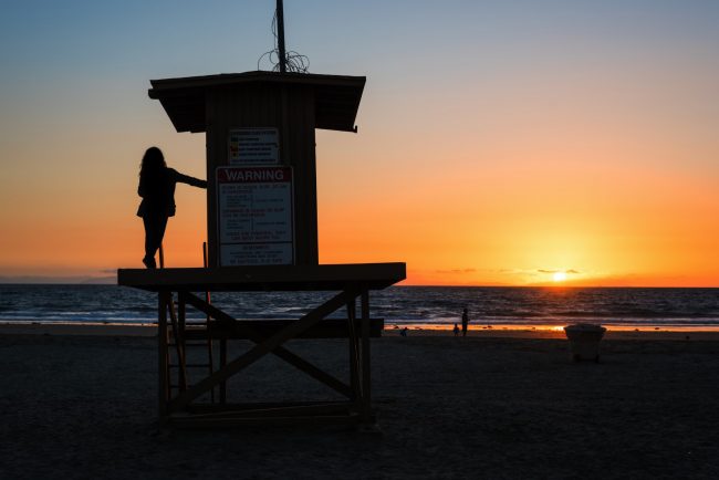 girl on a lifeguard tower in Newport Beach at sunset California